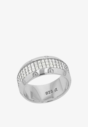 Srebrny pierścionek z szeroką obrączką, zdobioną rzędem małych błyszczących kamieni, gładką polerowaną powierzchnią oraz grawerowanymi detalami po wewnętrznej stronie.
