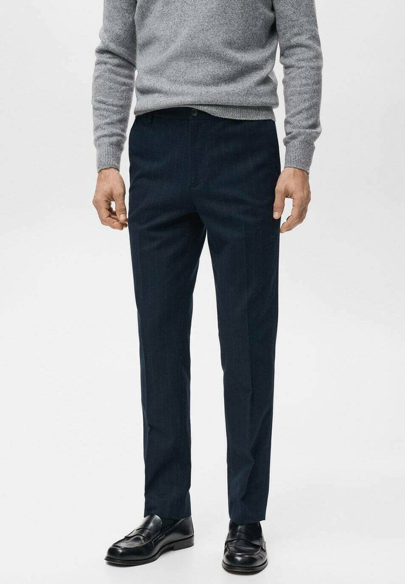 Granatowe spodnie w prążki wykonane z lekkiego materiału, o dopasowanym kroju, zestawione z czarnymi skórzanymi butami i szarym swetrem z dzianiny.