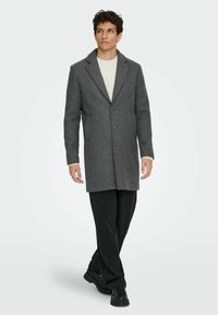 Grau Wollmantel mit Schalkragen, einreihigem Design, drei Knöpfen und Vorderaschen. Trägt man über einem leichten Pullover und Hose.