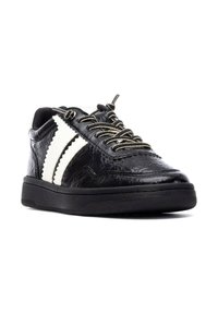Zapatilla negra de cuero con rayas blancas, parte superior texturizada y cordones metálicos. Presenta un cuello acolchado y suela plana de goma.