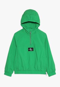 Zielona, lekka kurtka z kapturem, z półzamkiem, elastycznymi mankietami i pasem. Z przodu znajduje się czarna naszywka z logo.