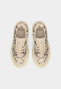 Paire de baskets beige et noir à motif serpent avec lacets et branding "Copenhagen Studios" à l'intérieur, vues de dessus sur fond blanc.