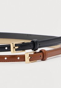 Δύο ζώνες, μία μαύρη και μία καφέ, και οι δύο κατασκευασμένες από λείο δέρμα. Κάθε μία διαθέτει αγκράφα από μεταλλικό υλικό σε χρυσή απόχρωση και πολλαπλές τρύπες για ρύθμιση.