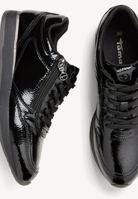 Schwarze Lackledersneaker mit strukturiertem Finish, ausgestattet mit einem seitlichen Reißverschluss, runden Schnürsenkeln und einem gepolsterten Knöchelkragen. Größe 39.