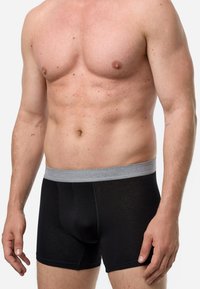 Schwarze Boxershorts mit einem grauen elastischen Bund, die eine glatte Textur und eine figurschmeichelnde Passform aufweisen. Der Stoff scheint leicht und atmungsaktiv zu sein.