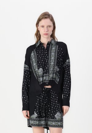 Abito chemisier nero con colletto a bottoni, maniche lunghe, modelli paisley e geometrici a contrasto in verde e bianco, vita regolabile con cordoncino.