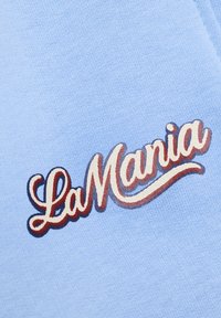 Svetlomodrá látka s mäkkou textúrou, na ktorej dominuje výrazné logo "LaMania" v štýlových bielych a marhuľových písmenách.