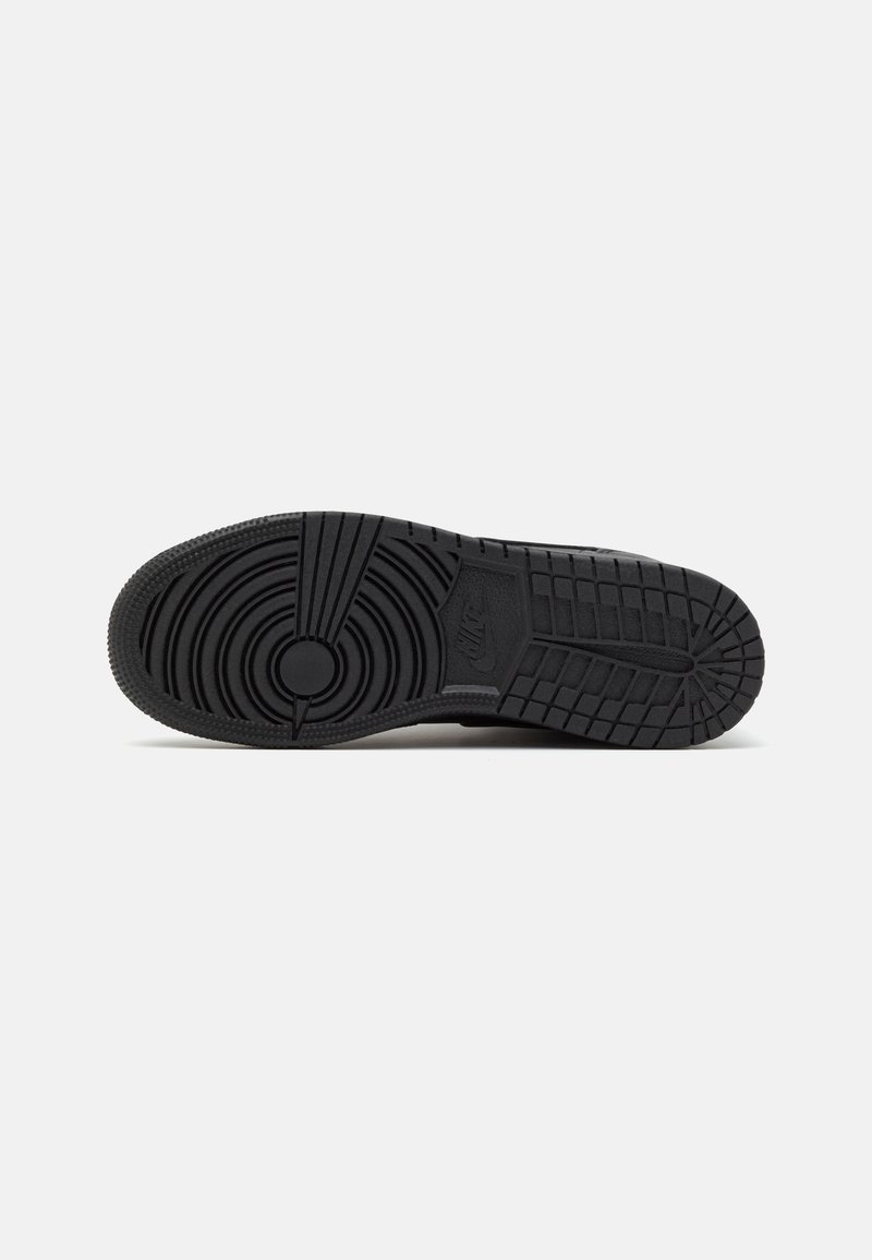 Semelle de sneaker noire avec des motifs de tread circulaires et linéaires. Fabriquée en caoutchouc avec des accents texturés pour une adhérence et une durabilité accrues.