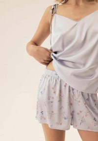 Jasnolawendowa koszulka na cienkich ramiączkach z dekoltem w kształcie litery V, połączona z szortami w kwiatowy wzór z elastycznym paskiem.