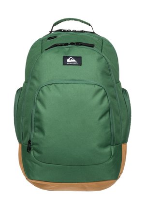 Grøn og brun Quiksilver rygsæk med flere lynlåslommer og et topgreb, vist mod en hvid baggrund.