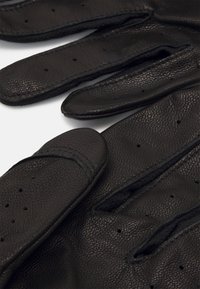 Sorte læderhandsker med en struktureret overflade, der har perforeringer på fingrene for åndbarhed og et glat, afrundet manchet-design.