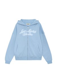Sudadera con cremallera de color azul claro con un logo en el frente que dice "Low Lights Studios", contando con mangas raglán y dos bolsillos laterales. Material de algodón suave.