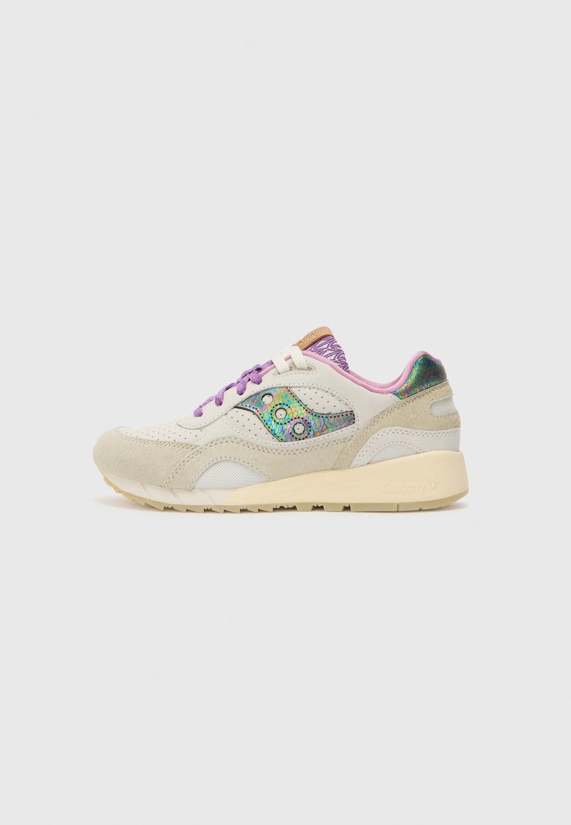 Zapatillas beige con cordones morados, materiales de gamuza y malla, acentos iridiscentes en los costados y una suela de goma de color claro.