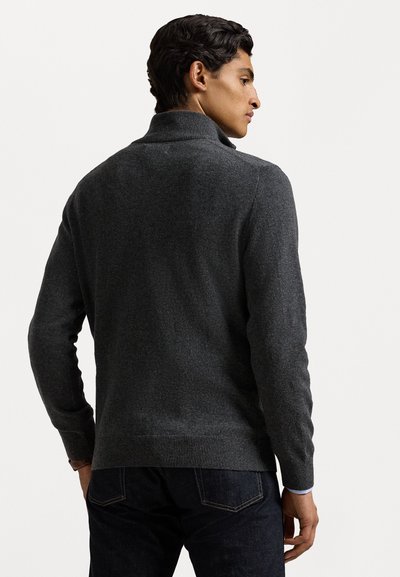 Grijze pullover trui met een geribde col. Heeft een textuur brei ontwerp en lange mouwen, gedragen over donkere jeans. Eenvoudig en modern.