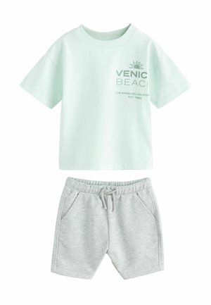 T-shirt à manches courtes vert menthe clair avec le texte "Venic Beach" ; associé à un short en coton gris clair avec une taille élastique et des poches.