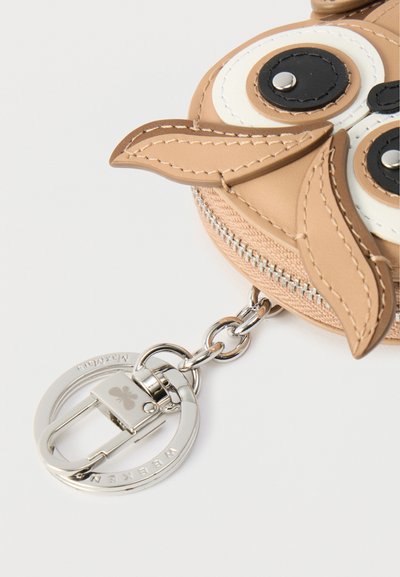 Πορτοφόλι σε σχήμα κουκουβάγιας κατασκευασμένο από ταμπά συνθετικό δέρμα με μαύρες και λευκές λεπτομέρειες, διαθέτοντας ασημένιο φερμουάρ και στρογγυλή βάση για κλειδιά.