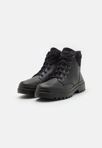 Botas de tobillo negras de cuero con una textura suave, que presentan un cierre de cordones en la parte delantera, cremallera lateral y suela robusta para mayor tracción.