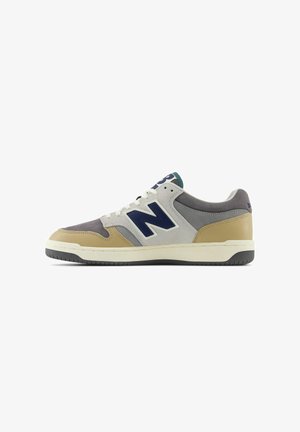 Zapatilla con una combinación de colores gris, marrón y azul marino. Presenta materiales de ante y sintéticos, un diseño de cordones y un destacado logo "N".