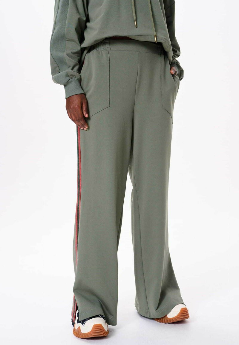 Olijfgroene comfortabele wijdlopende sweatpants met zijzakken, voorzien van een meerkleurige streep langs de buitennaad, gemaakt van zachte stof.