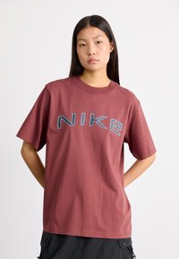 Camiseta de algodón en color burdeos con un audaz logo en gris de "NIKE" en el pecho, de mangas cortas y un diseño clásico de cuello redondo.