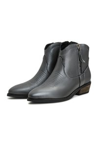 Botas de tobillo de cuero gris con punta afilada, costuras decorativas sutiles y cremallera lateral. El tacón de aspecto madera añade contraste.