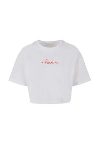 Bílý crop top vyrobený z bavlny, s krátkými rukávy a červenou grafikou "láska" s šipkami, umístěnou na hrudi.