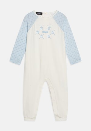 Biely overal s modrými raglánovými rukávmi, s hviezdnym vzorom a modrým logom "VERSACE" na prednej strane, vyrobený z mäkkého bavlneného materiálu.