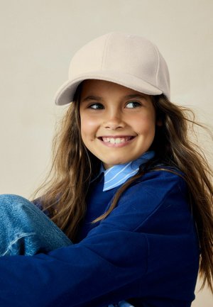 Hellbrauner Baseballcap aus weichem Material mit gebogenem Schirm. Der Träger hat lange braune Haare und trägt ein blaues Hemd mit einem hellblauen Kragen.