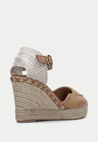 Espadrile na klínu s hnědou koženou špičkou, tkaným béžovým a bílým svrškem a texturovanou juty platformou. Disponuje přezkou kolem kotníku.