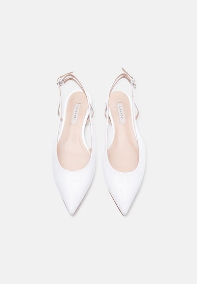 Λευκά ψηλοτάκουνα παπούτσια με αιχμηρή μύτη, δετά στον αστράγαλο, με μπεζ εσωτερικές επενδύσεις, τοποθετημένα δίπλα-δίπλα σε λευκό φόντο.