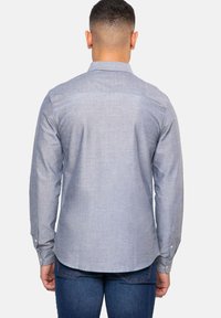 Lange mouwen knoop-overhemd van lichtblauwe stof. Beschikt over een gestructureerde kraag, back yoke-detail en een gebogen zoom. Knoppen bij de manchetten.