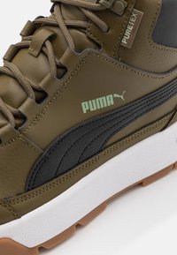 Olivgrüne Leder-Sneaker mit schwarzen Akzenten, strukturiertem Seitenstreifen, leichtem weißen Zwischensohle und brauner Gummisohle. Mit Logodetail.