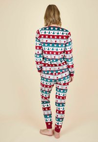 Rood en teal-gepatroneerde pyjama set met feestelijke beren en sneeuwvlokken. Zachte stof met lange mouwen en taps toelopende broekspijpen, voorzien van elastische manchetten.
