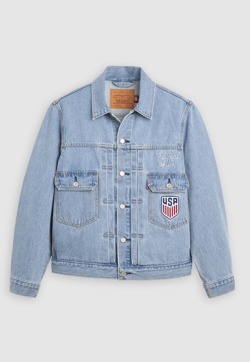 Veste en jean bleu clair avec fermeture à boutons, deux poches avant, texte « The Best of U.S. » et un écusson en forme de blason des États-Unis sur la poche poitrine.