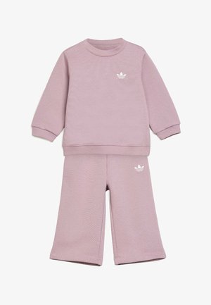 Sæt med lilla langærmet sweatshirt og bukser med brede ben med hvide Adidas trefoil-logoer på brystet og venstre lår.