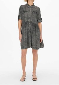 Lyhyt denimmekko tummanharmaana, jossa on kauluksellinen pääntie, nappikiinnitys edessä, kaksi rintataskua, vyötärö kerrostettu ja kääritty hihansuut.