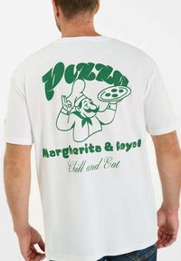 Witte t-shirt met groene grafische print van een chef met een pizza, met de tekst "PIZZA Margherita & Royal Chill and Eat."