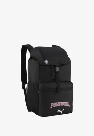 Mochila negra con solapa superior y bolsillo frontal con cremallera, con el texto "PORTUGAL" y el logo de Puma, además de un pequeño emblema en la solapa.