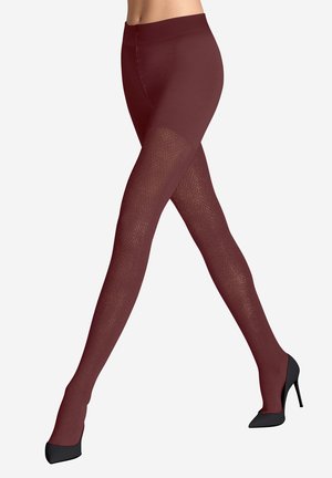 Beine, die bordeauxrote, strukturierte Sockenstrumpfhosen und schwarze High Heels tragen, sind im Schritt vor einem weißen Hintergrund übereinander geschlagen.