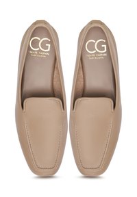 Moccasini din piele bej deschis cu o textură netedă. Au un vârf rotunjit, cusături contrastante și un logo embosat pe talpă.