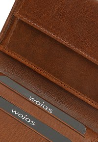 Brown leather wallet interior with card slots. Features visible stitching, smooth texture, and lined card holders displaying "wojas."