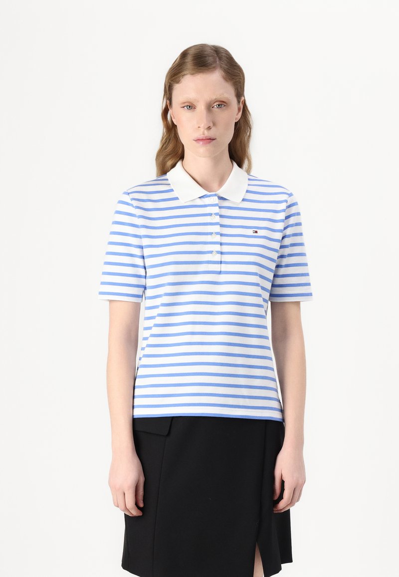 Polo shirt met blauwe en witte horizontale strepen, een witte kraag en een klein logo aan de linkerkant; korte mouwen en zachte stof.