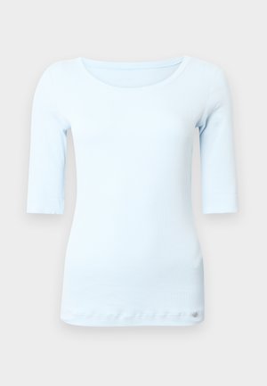 Light blue, fitted long-sleeve top with a round neckline and a soft, smooth texture. Features a small logo at the hem.