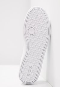 Semelle blanche de sneaker avec motif en arête de poisson, détail circulaire et logo "LACOSTE" embossé près du talon.