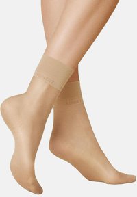 Beige Knöchelsocken aus glattem, transparentem Material, mit einem weichen Bund und dem "KUNERT"-Logo. Verlängerte Form mit nahtlosem Design.