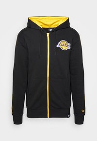 Svart zip-up hoodie med gula detaljer och foder i huvan. Har en broderad Los Angeles Lakers-logotyp på bröstet och sidofickor.