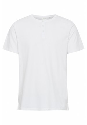 Valkoinen lyhythihainen t-paita pehmeästä kankaasta, jossa on pyöreä pääntie ja kolme nappia yksityiskohtana. Suora leikkaus ja sivu-avaukset.