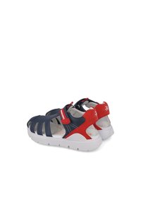 Sandalias en navy y rojo con un diseño transpirable, que presentan cortes, una correa de Velcro y una suela blanca con agarre texturizado para mayor comodidad.