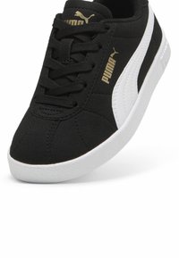 Sapatilha de camurça preta com detalhes brancos e uma sola de borracha texturizada. Apresenta atacadores pretos planos e a marcação em dourado da Puma na lateral.