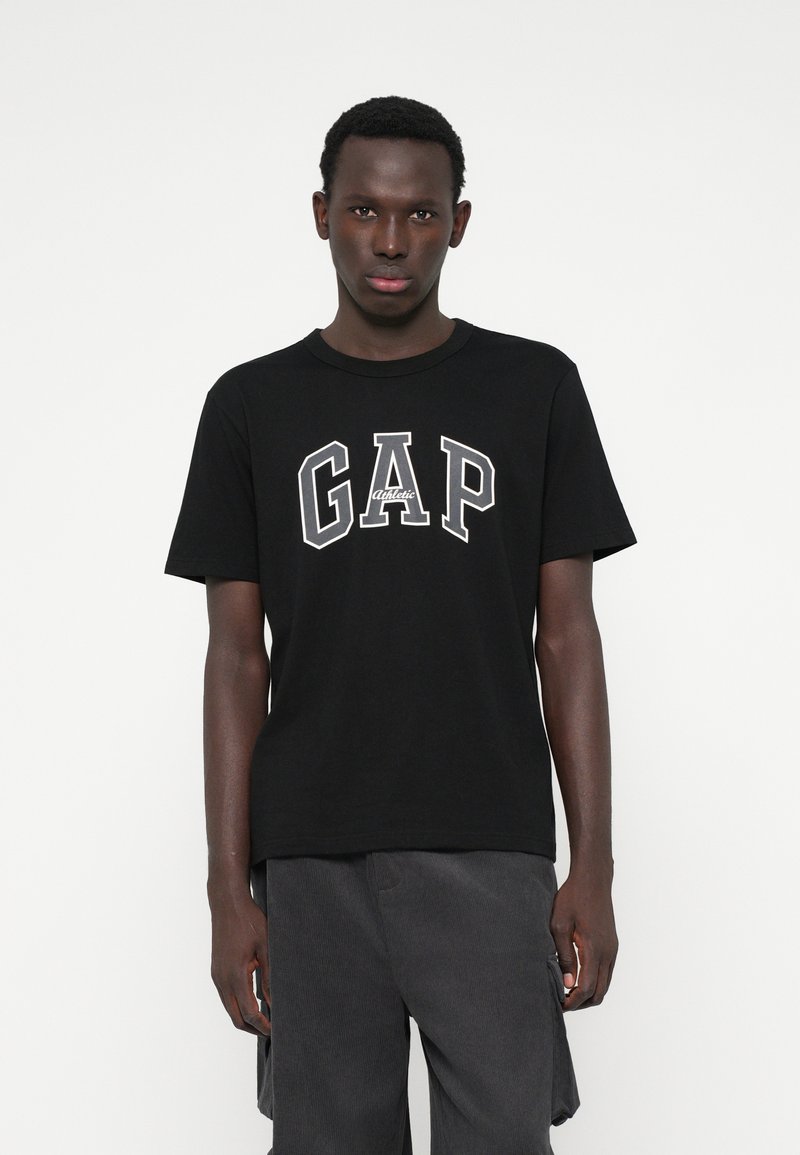 Czarna bawełniana koszulka z krótkim rękawem, z napisem "GAP" w pogrubionych, białych, konturowych literach; okrągły dekolt.